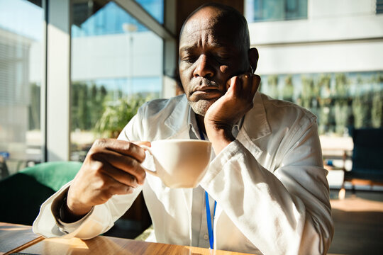 Tired doctor drinking coffee in hospital cafeteria