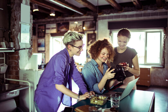 Three creative women reviewing photos in loft studio