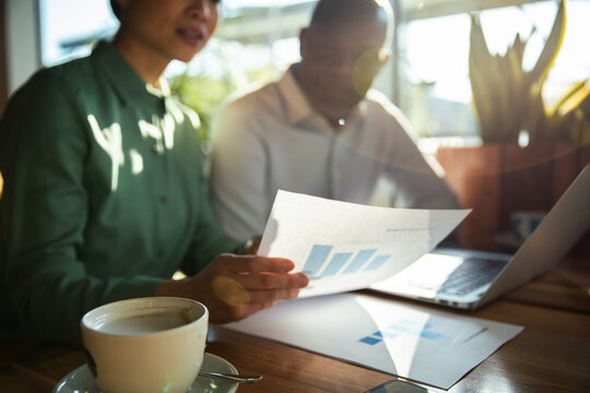 Coworkers reviewing financial report in sunlit office