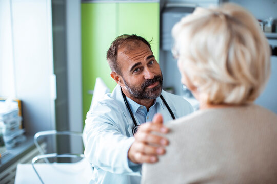 Male doctor comforting senior patient in clinic