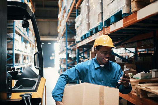 Smiling warehouse worker checking phone in distribution center