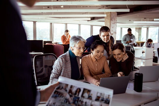 Multigenerational team collaborating on laptop in modern open office