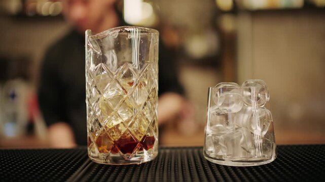 Professional bartender pouring liquor into a mixing glass with ice cubes