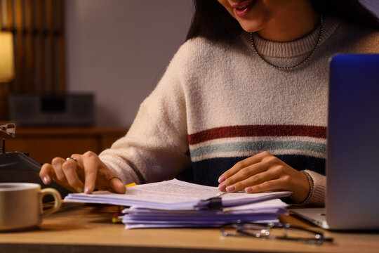 Female screenwriter with script on table in office at night, closeup