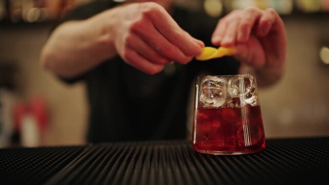 Close up of hands squeezing fresh lemon into a cocktail glass with ice