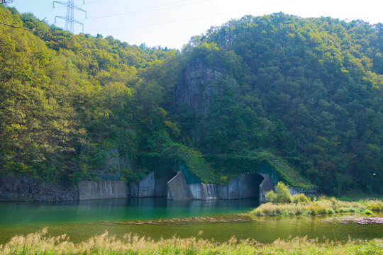 River Tunnel in Forested Cliff