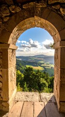 Fototapeta premium Stone archway frames rolling hills and sky. Light streams across the landscape