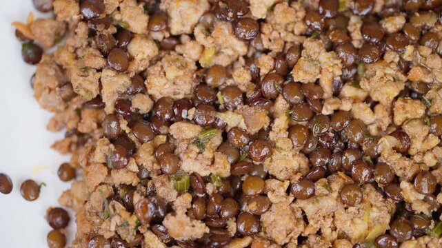Closeup of seasoned lentil mixture. Macro shot highlighting lentils meat and herbs. Highquality photograph capturing intricate details of nourishing lentil and meat dish
