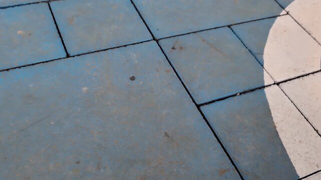 Blue paving tiles texture. Close up of concrete bricks with white painted line. Panning left on outdoor urban ground surface. Candid industrial street floor background.