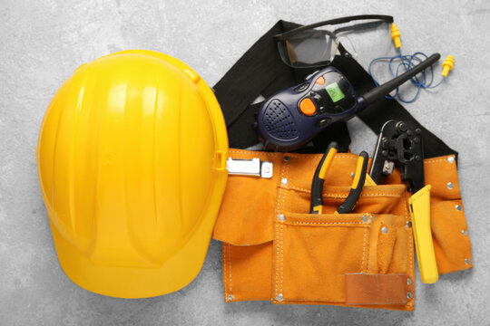 Hardhat with radio transceiver and safety equipment on grey grunge background