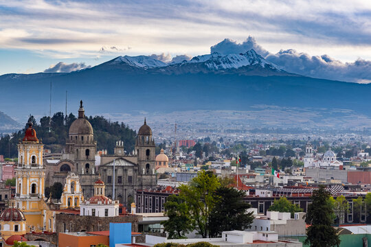 Panoramic view of Toluca city colonial churches and cathedral with snow-capped Nevado de Toluca volcano and dramatic clouds, State of Mexico, Mexico