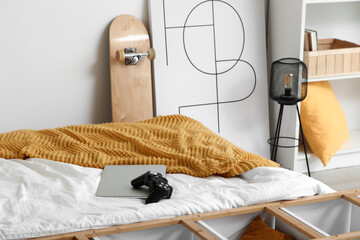 Laptop with game pad on teenager's bed in room © Pixel-Shot