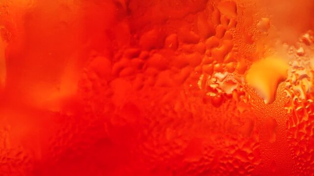 Macro shot of orange cocktail with bubbles and condensation creating an abstract background