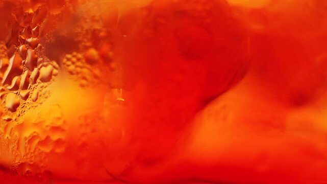 Macro shot of orange cocktail with bubbles and condensation creating an abstract background