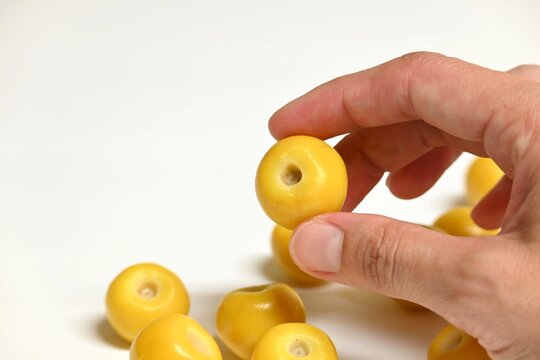 Hand Holding Fresh Nance Fruit (Byrsonima Crassifolia) Isolated on White Background