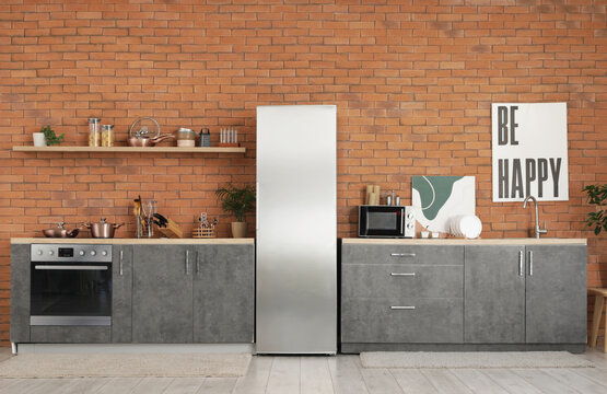 Interior of modern kitchen with silver fridge, counters and shelf