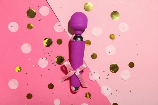 Composition with vibrator, bow and confetti on color background