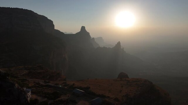 Drone view of the Gheralta Mountains, with rock faces and terrain of Ethiopia. Wide rotating aerial footage. Into the sun.