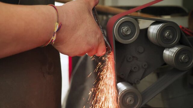 A hatchet is being sharpened on a grinding machine in Malaysia, with sparks flying, highlighting tool maintenance, precision work, and industrial craftsmanship.