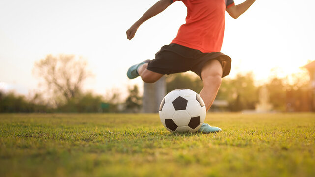 Action sport outdoors of kids having fun playing soccer football for exercise under the twilight sunset sky. Picture with copy space.
