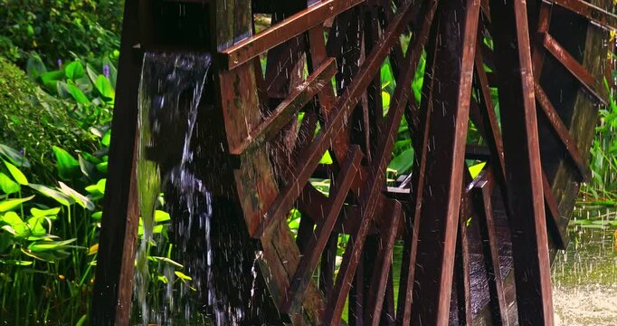 Close-up of a traditional wooden waterwheel operating in a garden pond.