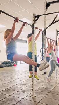 Athletic women doing kipping pull ups in gym