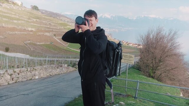 Photographer taking pictures in Lavaux during the day with Lake Geneva and mountains in Canton of Vaud, Switzerland, handheld shot