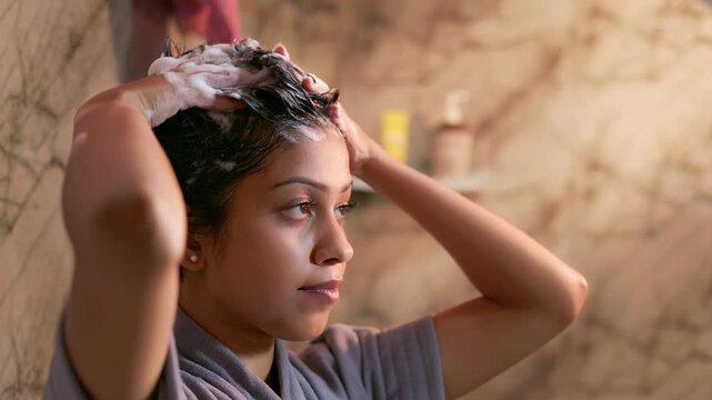 An Indian woman cleansing her hair with shampoo in the bathroom during morning haircare routine.