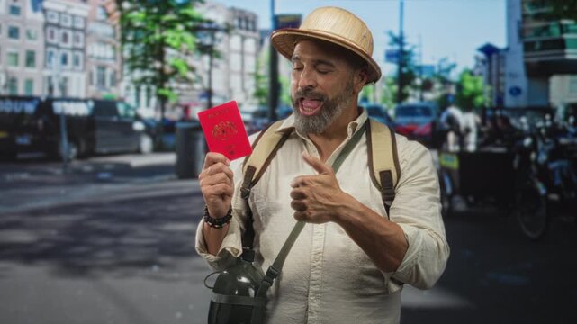 Man holding passport and giving thumbs up on city street with backpack and canteen visible; adventure excitement.