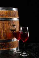 Fototapeta premium Wooden barrel with glasses of wine on dark background