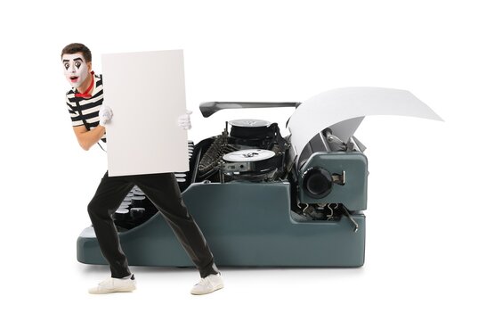 Male pantomimist with blank poster and big typewriter on white background