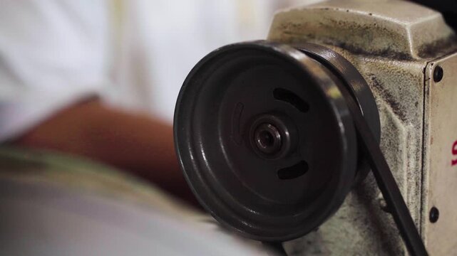 Close-up of a flywheel of a sewing machine stitching fabric in Malaysia.
