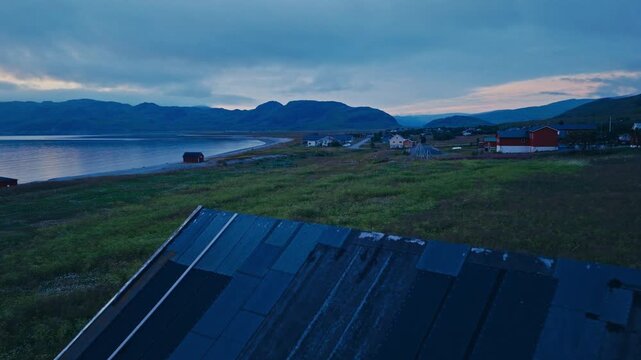Kokelv, Hammerfest, Finnmark, Norway - The View Showcases Colorful Houses Along the Calm Sea, With Mountains in the Distance - Drone Flying Forward