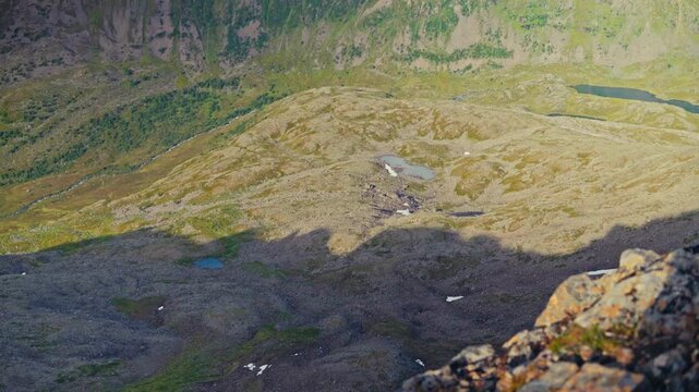 Middagsfjellet, Sandland, Nordkapp, Finnmark, Norway - The Mountain Range Stretches Across the Horizon, With a Green Valley and Serene Lake Below - Pan Up Shot