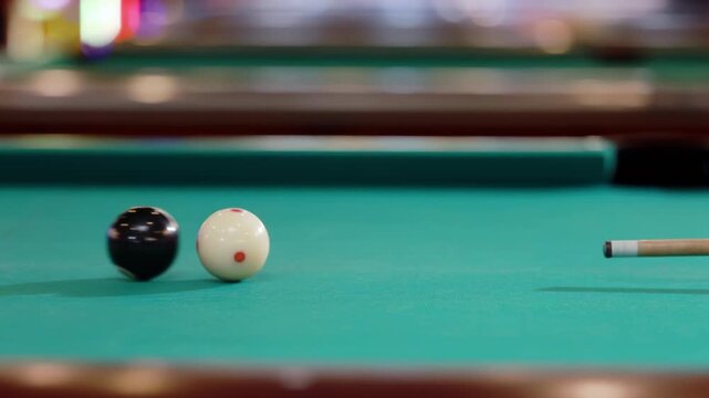Billiard pool table shows black 8 ball arranged for game play, is hitting by the white cue ball with the cue, vintage pool game object with number eight, showing signs of age use. Classic cue sport