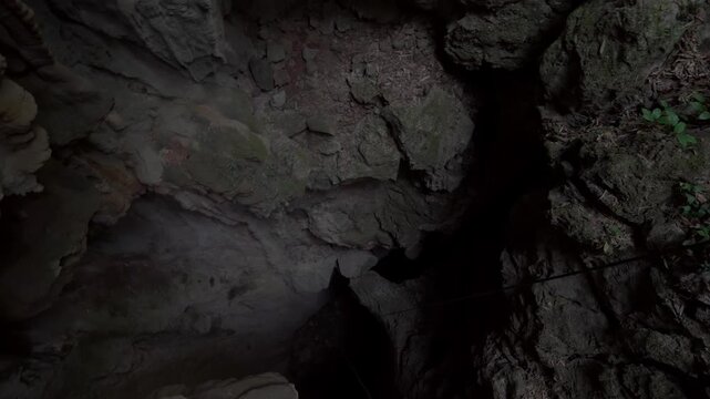 POV shot hanging from a rope abseiling down into the abyss, camera looking down into Tham Pong sinkhole in Laos.