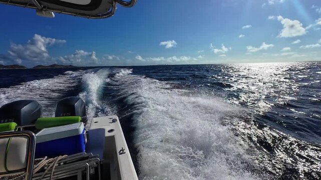 wide shot from the stern of a speedboat, showing the white foam trail and powerful outboard engines during a sunny day trip.