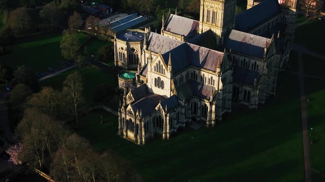 Aerial close view of Salisbury Cathedral showing detailed gothic architecture roof structure and stonework in warm evening light Wiltshire England