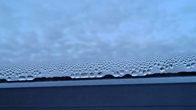 Condensation water droplets on a window glass, wet surface background, home humidity and moisture problem concept