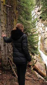 A girl in the mountains near a waterfall in early spring.