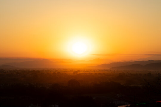 Beautiful golden sunset over mountains and countryside landscape, creating a warm and peaceful atmosphere.