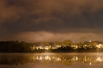 Naklejka premium Misty Lakeside Village at Night