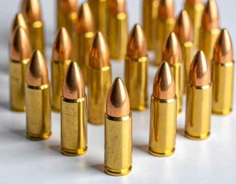Ammunition bullets stand, golden casings and copper tips, arranged densely on a white surface in crisp focus