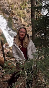 A woman against the backdrop of a mountain waterfall.