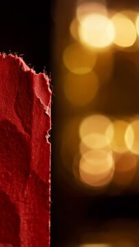 Macro close up of torn movie ticket stub edge with red texture against warm golden bokeh background, highlighting paper fiber details and cinematic lighting for nostalgic atmosphere.