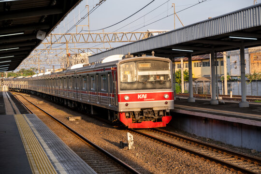 Tangerang, Indonesia - March 24, 2026: A KAI Commuter train at Tangerang Station during golden hour, with warm sunlight hitting its long train formation at the platform under a station roof structure.