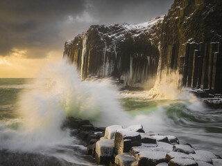 Obraz premium Atmospheric Basalt Formations Under Dramatic Skies and Ocean Spray