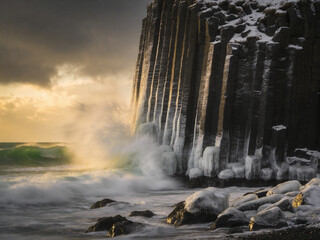 Obraz premium Atmospheric Basalt Formations Under Dramatic Skies and Ocean Spray
