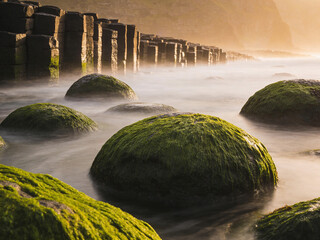 Obraz premium Atmospheric Basalt Formations Under Dramatic Skies and Ocean Spray