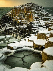 Obraz premium Atmospheric Basalt Formations Under Dramatic Skies and Ocean Spray